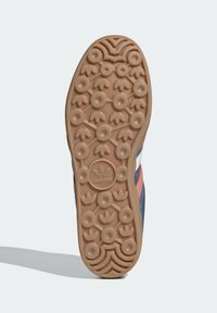 Podešev gumové tenisky s texturovaným vzorem obsahujícím kruhové tvary. Barva: světle hnědá s oblými designovými prvky a detailním logem.