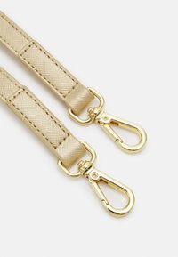 Beige nylon strap with gold-tone metal clips, featuring a textured surface and reinforced stitching for durability.