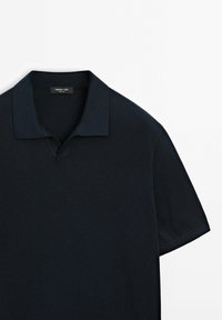 Laivastonsininen poolopaita, jossa on V-aukko, lyhyet hihat ja teksturoitu neulottu kangas. Sisäkauluksessa on hillitty merkkilogo.