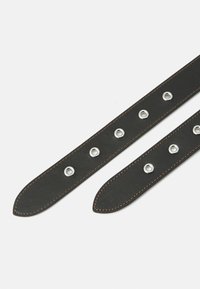 Black leather straps featuring silver grommets and contrasting brown stitching, with a pointed end for a secure fit.