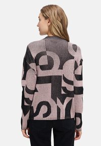 Strickpullover mit einem pink-schwarzen Farbschema und kräftigen Textmustern. Er hat eine gerippte Textur und eine lockere Passform.