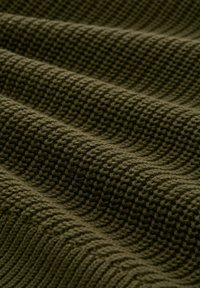 Zielono-oliwkowy teksturowany materiał z wplecionym wzorem, prezentujący miękką i lekko wypukłą powierzchnię w równomiernych, falistych fałdach.