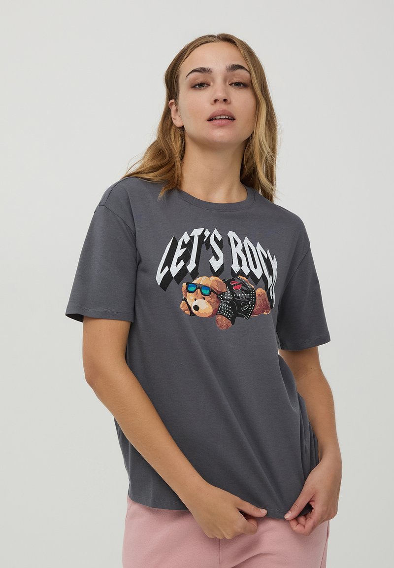 T-shirt grigia in cotone con una grafica di un orso che indossa occhiali da sole e una giacca di pelle, con il testo "LET'S ROCK" in carattere grassetto.