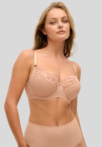 Vaaleanpunainen alusvaate rintaliivit, joissa koristelace-kuvio ja tukevat kaaritangot. Säädettävät olkaimet ja pieni rusetti keskellä.