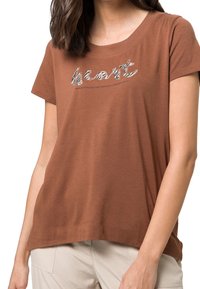 Brun kortærmet t-shirt lavet af blødt bomuld, med et struktureret sølv "hjerte" grafik og en rund halsudskæring. Glat stoffinish.