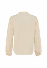 Blouse beige à manches longues avec détail froncé sur les épaules et poignets élastiques, vue de dos sur fond blanc.