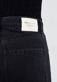 Crne traperice viskog struka, s oznakom "ONLY blue Denim" i poštarskom džepom na stražnjoj stranici.