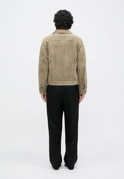 Μπεζ σουέντ σακάκι με διαρθρωμένους ώμους, ρέλι πίσω και δύο τσέπες. Συνδυασμένο με μαύρα παντελόνια ευρείας γραμμής.