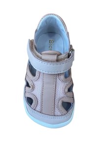 Sandal de color rosa claro, hecho de cuero y malla, con diseños recortados, una tira de Velcro y una suela de goma blanca.