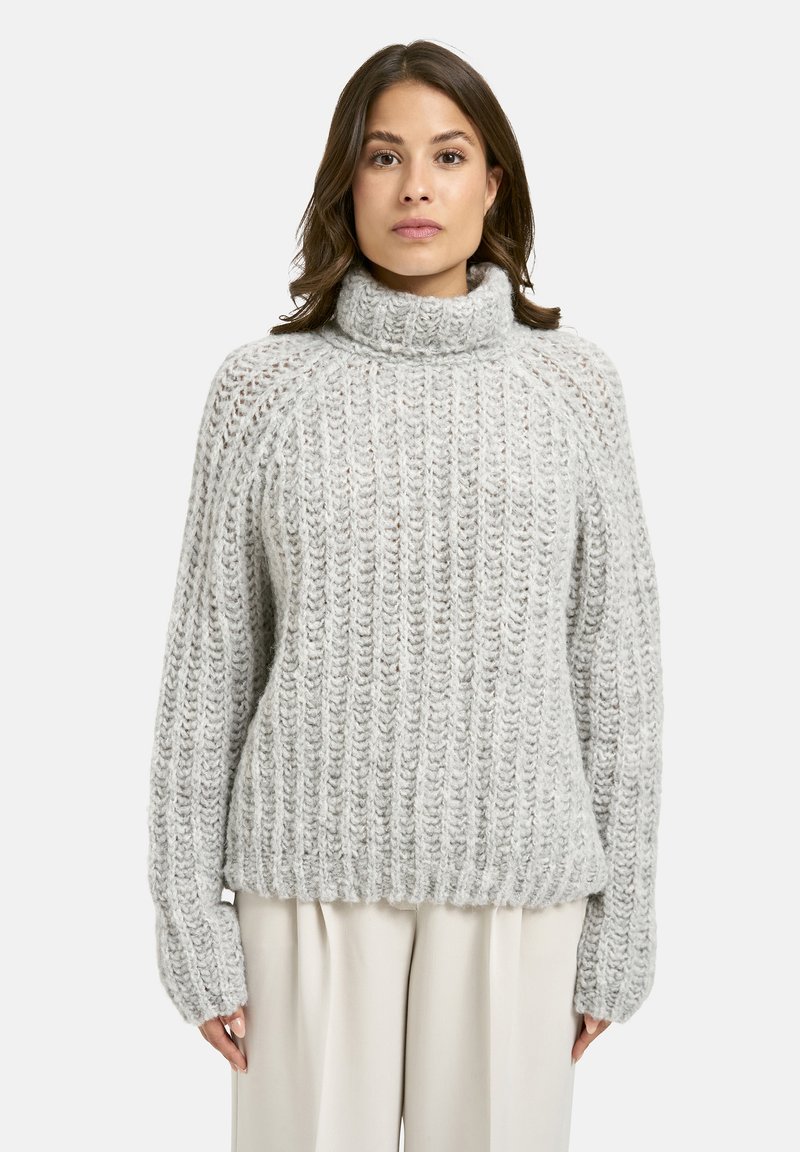 Helle graue Strickjacke mit einer groben Textur, hohem Rollkragen und geripptem Saum. Verfügt über lange Ärmel und eine lockere Passform.