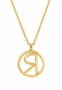 Złoty naszyjnik z zawieszką w kształcie koła z stylizowaną literą "R" w środku, zawieszony na delikatnym łańcuszku.