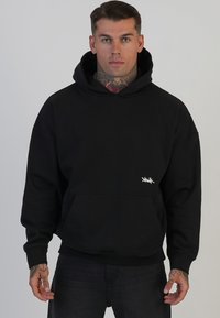 Črna kapuča z žametom, ki ima sprednji žep, rebraste manšete in majhen bel logotip na spodnjem levem delu.