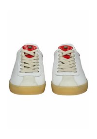 Bílé tenisky s gumovou podešví, featuring šněrování, červené akcenty na jazyku a hladkou koženou texturou.