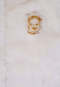 Tessuto in pelliccia sintetica bianca con un design ricamato a forma di faccia di maiale dorato. La texture è morbida e soffice, creando un aspetto accogliente.