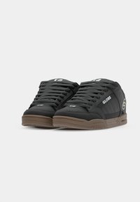 Pair of black Globe brand sneakers with brown soles, black laces, and logo detailing on sides and tongues, shown from front angle.