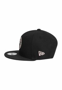 Schwarze Snapback-Cap aus strukturiertem Gewebe. Mit einem runden Logopatch auf der Vorderseite und einem kleinen rosa Logo an der Seite.