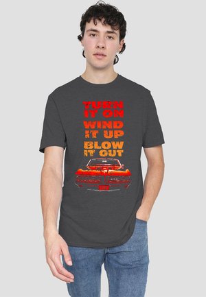 Gray t-shirt featuring bold, distressed text in red and orange reading: "TURN IT ON WIND IT UP BLOW IT OUT," with an illustration of a red car design.