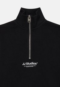 Pullover nero con zip a quarto di pollice realizzato in tessuto morbido; presenta una zip argentata, un colletto alto e il logo della marca bianco sul davanti.