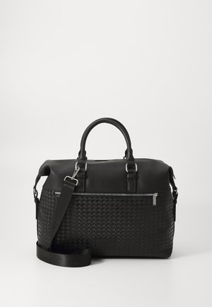 Schwarze Duffel-Tasche aus Leder mit strukturiertem, gewebtem Design, ausgestattet mit einem oberen Griff, einem verstellbaren Riemen und einem Reißverschlussfach.