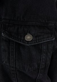 Fekete farmerdzseki zsebe, fedéllel, melyet egy 