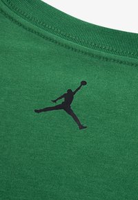Zielony bawełniany t-shirt z czarnym logo Jumpman przy dekolcie. Tkanina ma gładką fakturę z subtelnym wzorem dzianiny.