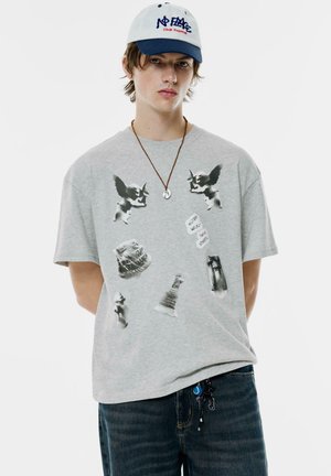Grå bomulds t-shirt med sorte grafiske print af forskellige objekter, herunder skulpturer og skakbrikker, i en afslappet pasform.
