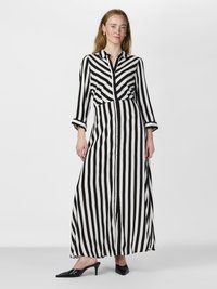 Črno-bela prožna obleka maxi z dolgimi rokavi in gumbastim zapiranjem spredaj. Ima prilegajoče se pas in razširjen krilo.