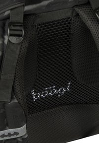 Czarny plecak z siateczkowymi detalami, wyposażony w szare logo Batmana i wytrzymałe paski. Materiał ma teksturowane wykończenie.