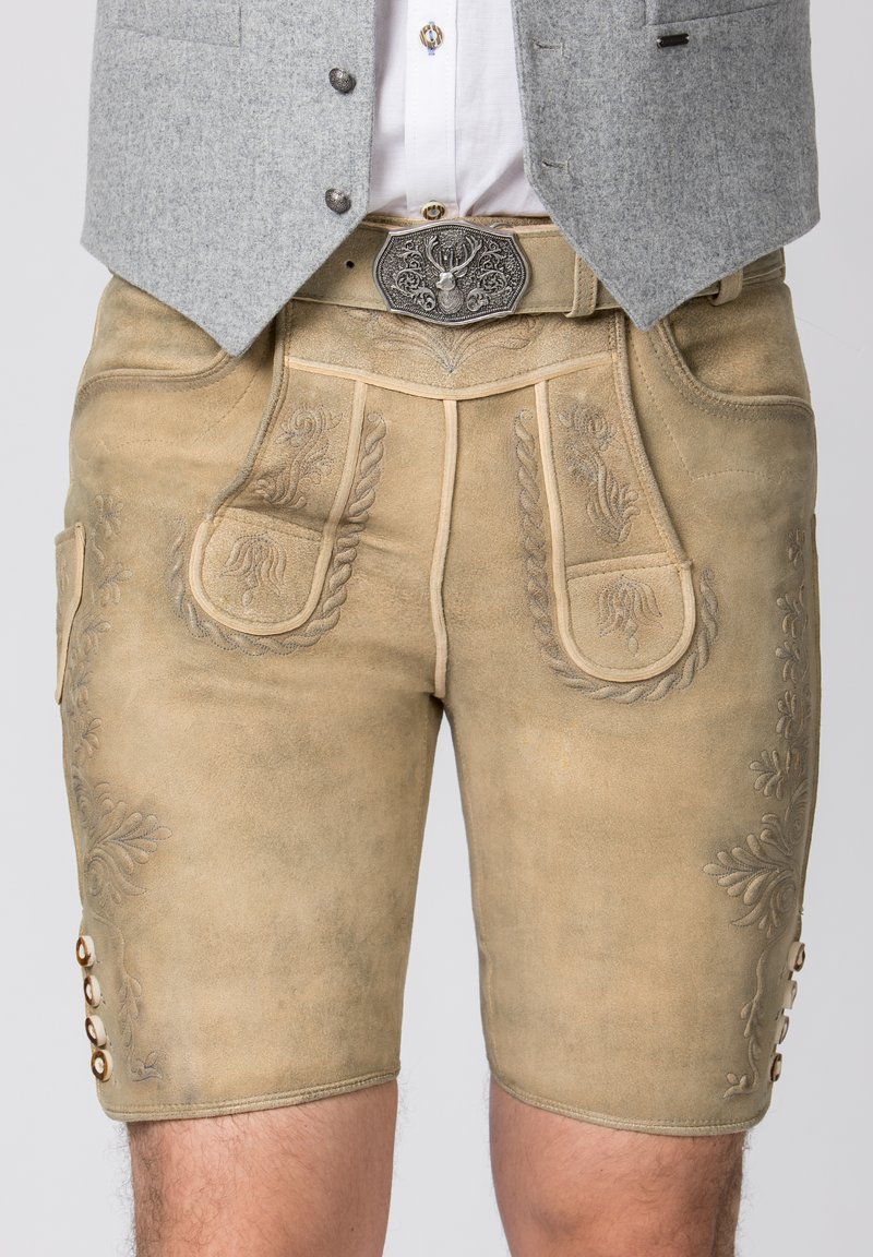 Lederhosen in einem hellbeigen Farbton mit dekorativer Stickerei, zwei Fronttaschen und einem geknöpften Seitendetail. Akzentuiert mit einer metallenen Gürtelschnalle.
