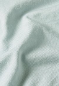 Világoskék, finom bordázott anyag, amely puha tapintású, finom redők és lerakás látható rajta, hangsúlyozva a sima és egyenletes felületi mintázatot.