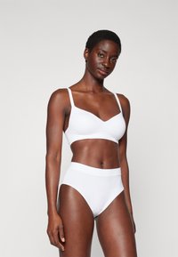 White bra and high-waisted panty set made of smooth fabric. Bra features thin straps and a v-neck design; panty has a soft waistband.