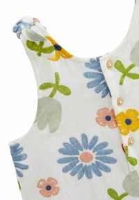 Robe sans manches à motif floral en tissu blanc. Ornée de fleurs bleues, roses, jaunes et vertes, avec des boutons en bois et des bretelles nouées.