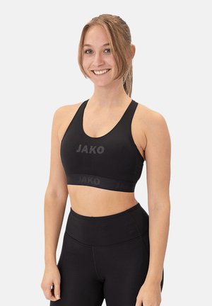 Reggiseno sportivo nero con branding JAKO, realizzato in tessuto liscio e elasticizzato. Presenta una fascia larga sul fondo e un design a manica racer.