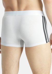 Vita boxershorts med en åtsittande passform, som har en mjuk midja och tre svarta vertikala ränder på sidan. Slät bomullstextur.