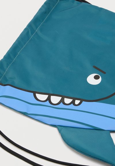 Μπλε πουγκί με σχέδιο καρτούν καρχαρία που δείχνει μάτι, δόντια και πτερύγιο σε λευκό φόντο.