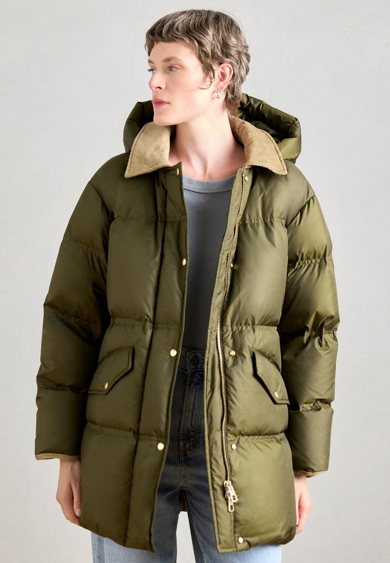 Parka căptușit în verde măsliniu cu o căptușeală din blană artificială bej, având fermoar frontal, capse și buzunare laterale. Țesătură netedă, rezistentă la apă.