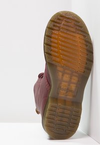 Stivale in pelle color marrone scuro con suola in gomma testurizzata e scanalata. Presenta dettagli di cucitura e un anello sul tallone per facilitare la calzata.