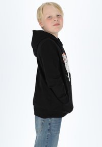 Black hoodie made of soft fabric, featuring a kangaroo pocket, colorful graphic print on front, and ribbed cuffs. Worn with blue jeans.