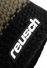 Black and tan knitted hat featuring a textured pattern and a prominent black rubber logo patch that reads "reusch" in white letters.