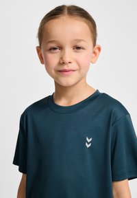 Teal kortärmad t-shirt i mjukt material med en rund halsringning och en liten grå logotyp på vänster bröst.