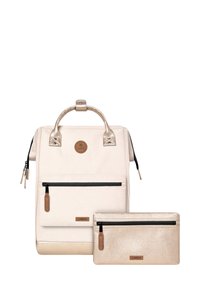 Sac à dos couleur crème avec des accents dorés brillants, comportant une poche zippée à l'avant et accompagné d'une petite pochette zippée dorée. Finition texturée.