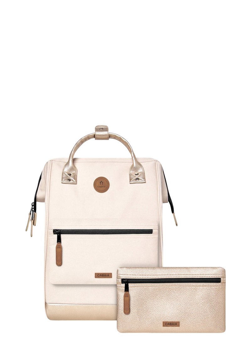 Sac à dos couleur crème avec des accents dorés brillants, comportant une poche zippée à l'avant et accompagné d'une petite pochette zippée dorée. Finition texturée.