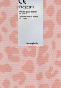 Texturerat material i ljusrosa med ett leopardmönster i mörkare rosa; inkluderar etikett med skötselråd och säkerhetsvarningar.