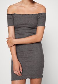 Robe grise à côtes, décolletée sur les épaules, avec des manches courtes, au design ajusté et à l'ourlet festonné. La texture lisse améliore l'apparence générale.