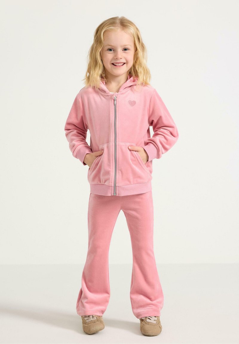 Růžový vlněný teplákový komplet s propínací mikinou, která má detail srdce, doplněný o rozšířené kalhoty. Měkká textura a neformální styl.