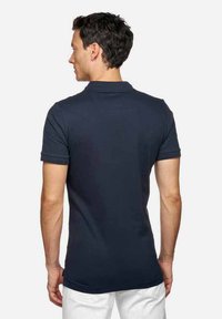 Polo de color azul marino con mangas cortas, un cuello y un dobladillo recto. El material parece suave y ligero, adecuado para un uso casual.