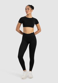 Zwart atletisch cropped top en hoge taille legging gemaakt van rekbaar materiaal. Heeft een aangesloten ontwerp met minimale naden en merkspecificaties.