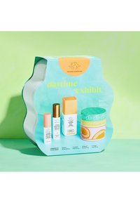 Daytime Exhibit skincare set with four colorful bottles and jars on a wavy light blue package, against a light green background.