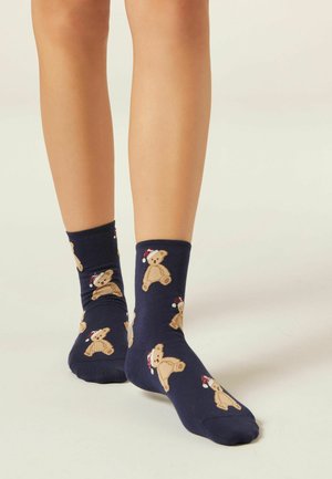Navy blue cotton socks featuring a repeating pattern of teddy bears wearing red and white hats. Ribbed cuffs above the ankle.