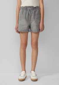 Szare dżinsowe szorty z elastycznym pasem, regulowanym sznurkiem i bocznymi kieszeniami. W połączeniu z białymi trampkami dla swobodnego looku.